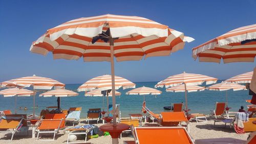 Parasols on beach against clear blue sky