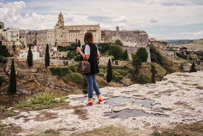 Full length rear view of woman standing against buildings in city