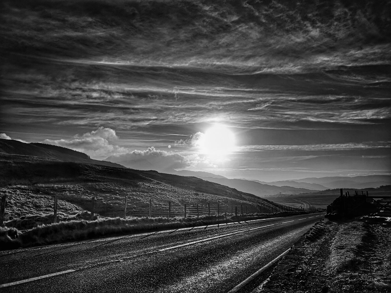 darkness, transportation, sky, horizon, road, black and white, cloud, monochrome, environment, nature, light, monochrome photography, landscape, the way forward, scenics - nature, no people, beauty in nature, sunlight, mode of transportation, morning, mountain, outdoors, black, travel, vanishing point, land, tranquility, dawn, highway, street, sunbeam, non-urban scene, tranquil scene