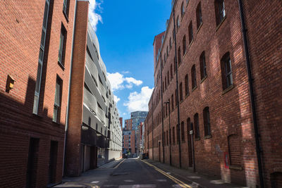 Empty road amidst buildings against sky