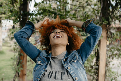 Portrait of smiling young woman with arms raised