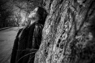 Side view of woman standing by tree