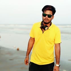 Portrait of young man wearing sunglasses while standing at beach