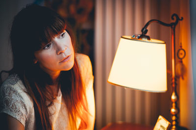 Close-up of young woman looking at illuminated lamp