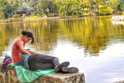 Young woman sitting by lake