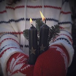 Midsection of child holding lit candles during winter