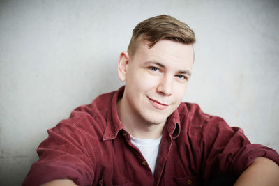 Close-up portrait of young male student against wall in university