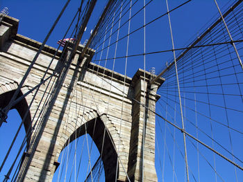 Low angle view of suspension bridge against blue sky