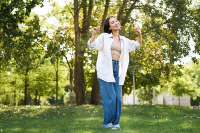 Young woman standing against trees