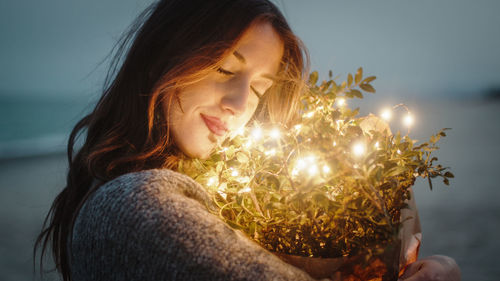 Sweet girl squeezes to herself bouquet of flowers with lights