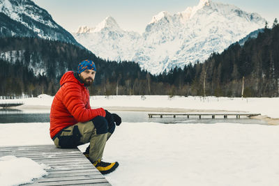 Rear view of man sitting on snowcapped mountain