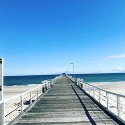 Pier over sea against clear blue sky