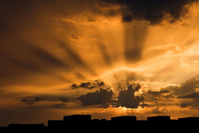 Low angle view of silhouette buildings against dramatic sky