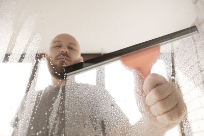 A male washes windows at home. house cleaning. cleaning a glass with a squeegee, close up.