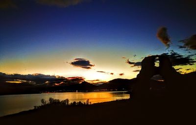 Silhouette trees by lake against sky during sunset