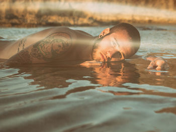 Portrait of shirtless man relaxing in lake