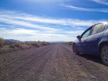 Cars on road against cloudy sky