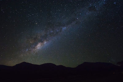 Low angle view of silhouette mountain against sky at night