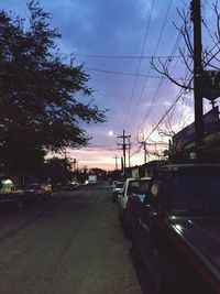 Cars on road in city against sky during sunset