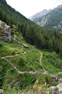 People walking lined up in a footpath in italian alps, lillaz, aosta, italy