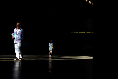 Rear view of people standing in illuminated building