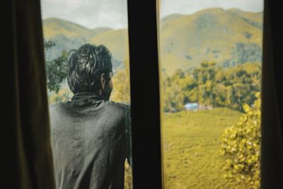 Rear view of man looking through window