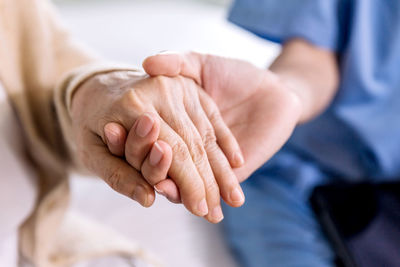 Close-up senior asian woman hand with her caregiver helping hands holding together, caregiver visit.