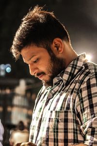 Bearded young man looking down at night