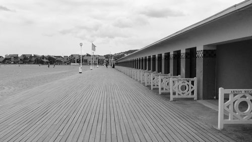 Empty footpath amidst buildings against sky