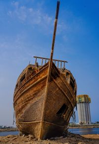 Low angle view of abandoned ship on beach against sky