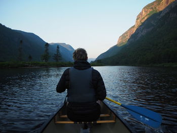 Rear view of man looking at lake against mountain range