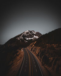 Road leading towards mountain against clear sky