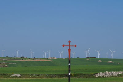 Windmills on field against sky