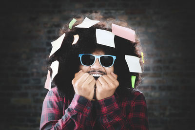 Portrait of young man wearing sunglasses against wall