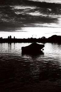 Silhouette boat in lake against sky during sunset