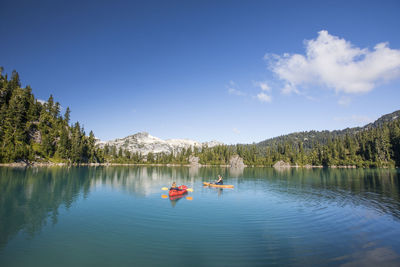 Mother and daughter float on beautiful blue alpine lake.