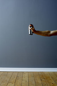 Low section of man holding umbrella on wooden floor