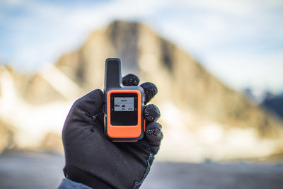 Mountaineer checks weather on small satellite communication device.