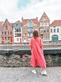 Rear view of woman walking against buildings in city