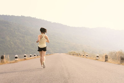 Rear view of woman running on road