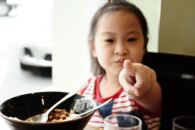 Close-up portrait of girl eating food in bowl at restaurant