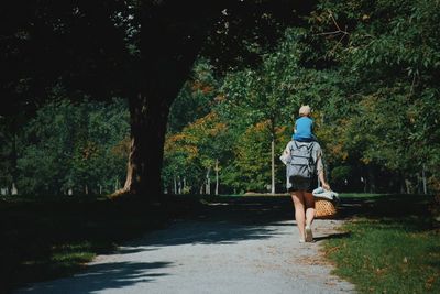 Rear view of woman walking on footpath amidst trees