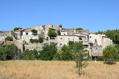 Houses on field against clear blue sky