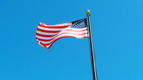 Low angle view of american flag against blue sky