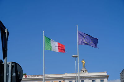 Italian and european flags fluttering against blue sky