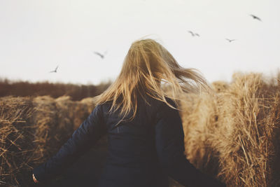 Rear view of woman standing on field against clear sky