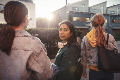 Female teenager friends on footpath during sunset