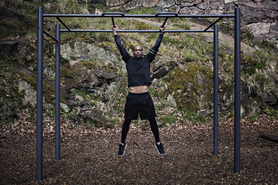 Full length of man exercising on monkey bars at outdoor gym