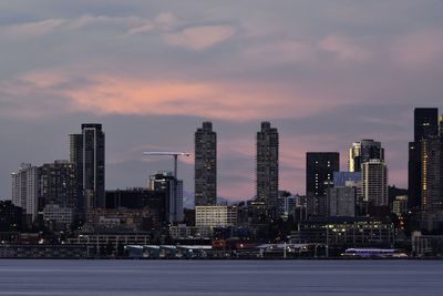 Modern buildings in city against sky at sunset