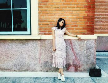 Portrait of woman standing against brick wall